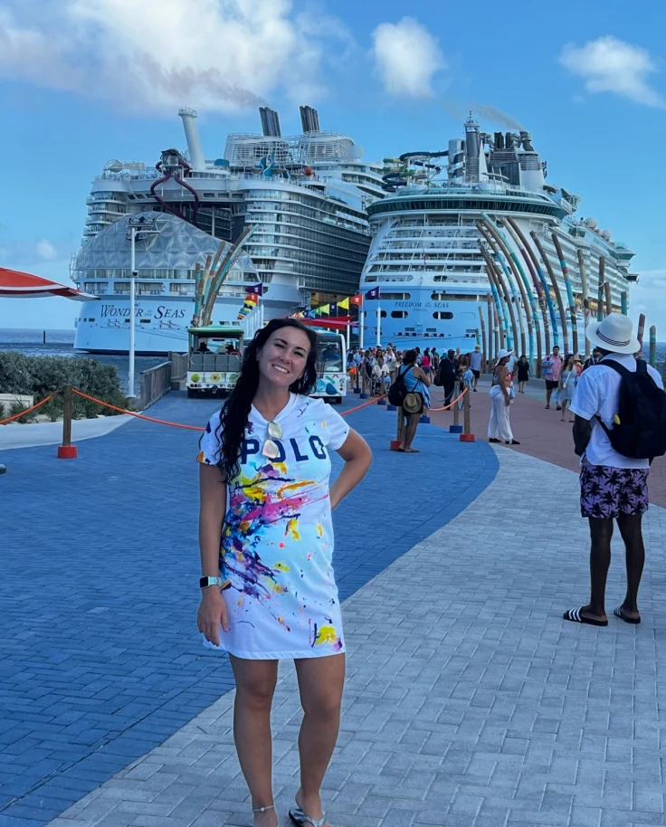 A posing standing and posing for a photograph in front of two large cruise ships