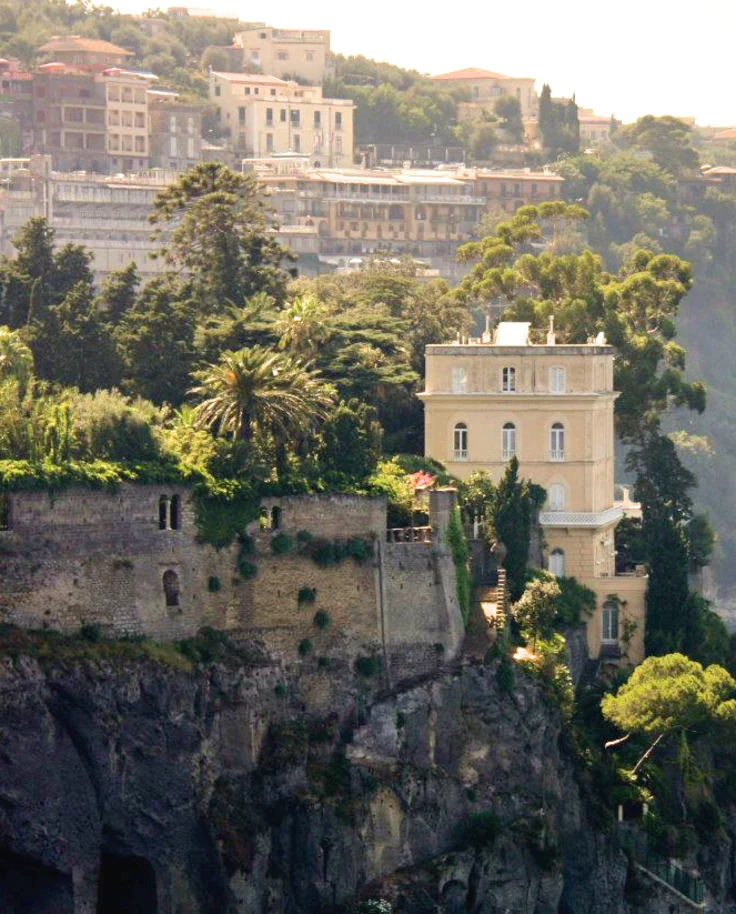 A building on the cliffside with a view of other buildings in the distance