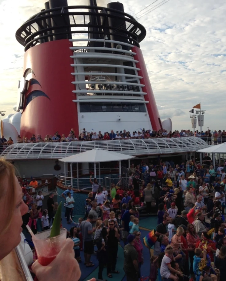 A large crowd of people on the deck of a cruise ship at the Disney Wonder Party.