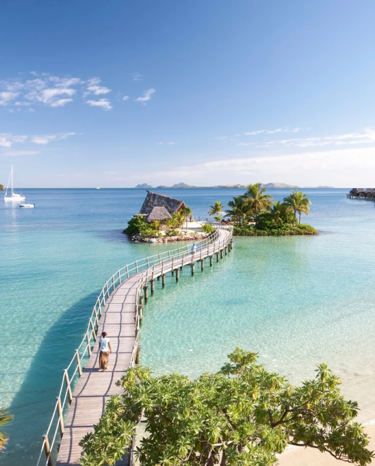 A bridge over bright blue water leading to an island resort