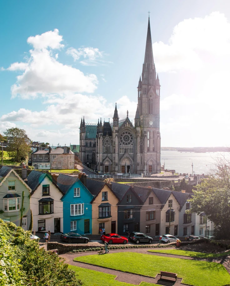 A cathedral and colorful houses in County Cork, Ireland, by the sea.