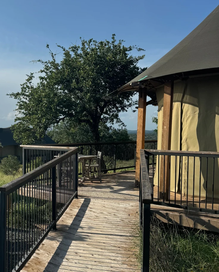 The outside of a tent with a terrace overlooking trees