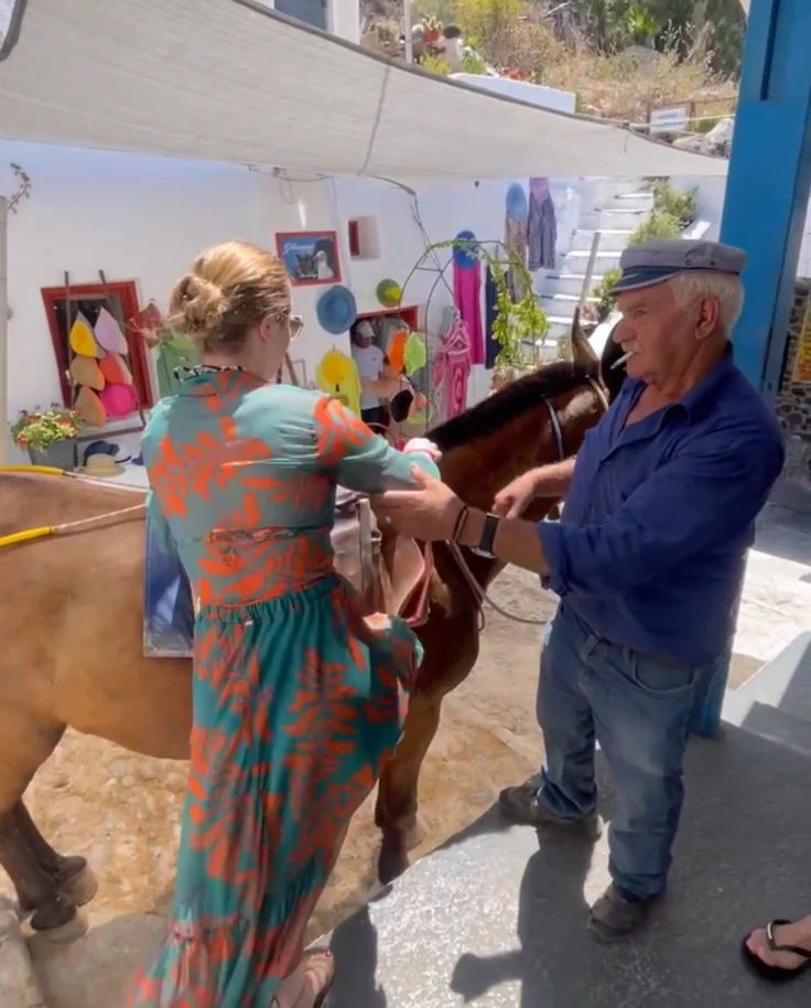 Travel advisor Elaine mounting a donkey with the help of a man in a Greek street