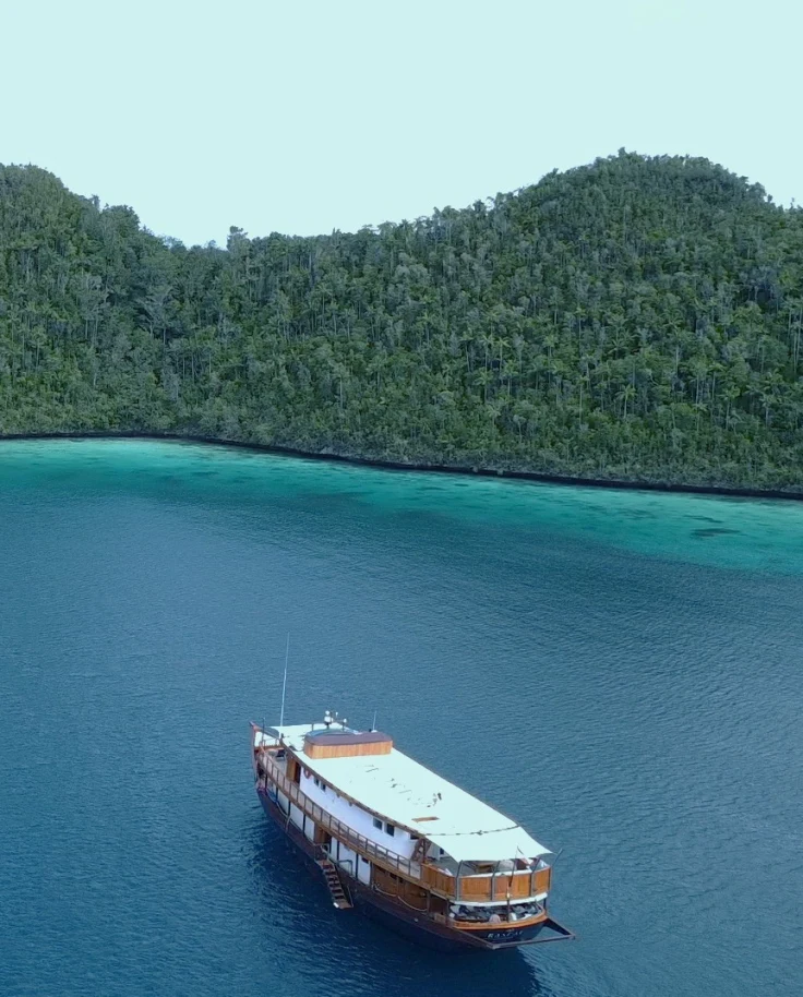 A yacht cruise in the sea with sandy enclave in the distance.