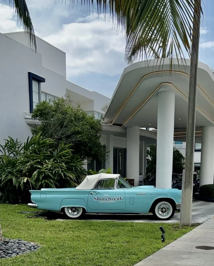 entrance to the hotel with a classic car parked in front with palm trees