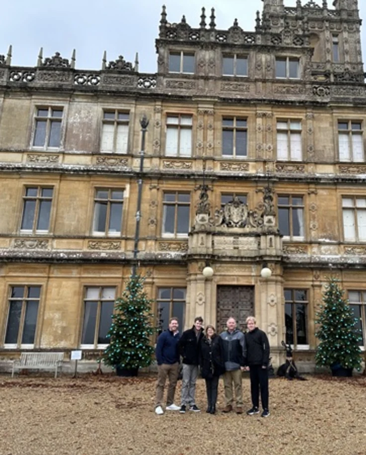 A group photo before the Highclere Castle in England, on a mildly foggy day.