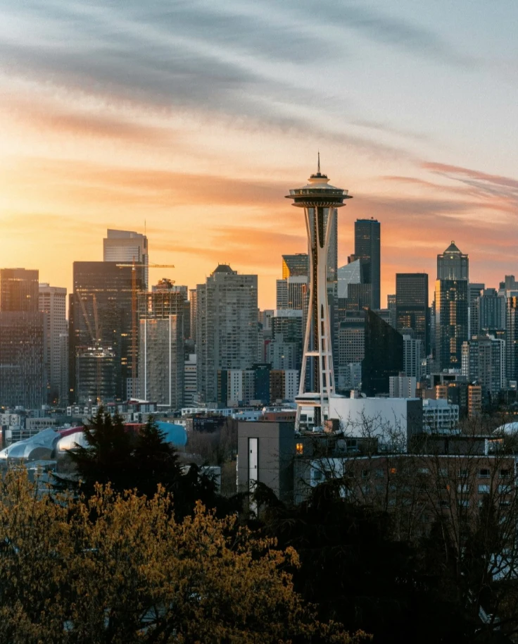 A view of the stunning Seattle skyline with a vibrant, orange sunset in the background.