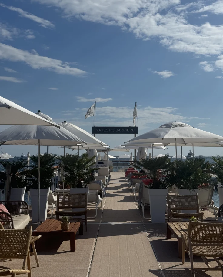 View of the pool surrounded by loungers and umbrellas on a sunny day.