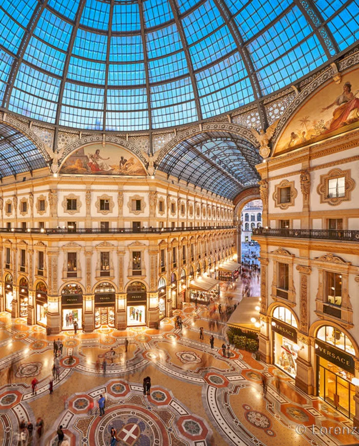 A vast gallery building adorned with gold features and a glass, domed ceiling