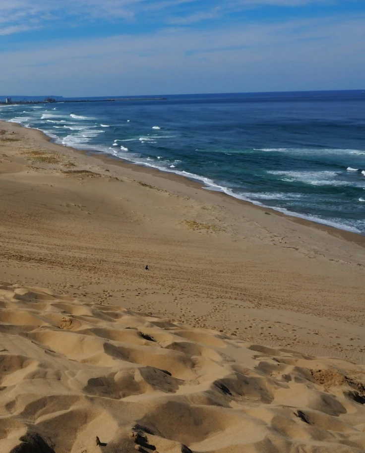 A beach with golden sand and blue water at Tottori Sand Dunes, frequently mistaken for Hokkaido Beach.
