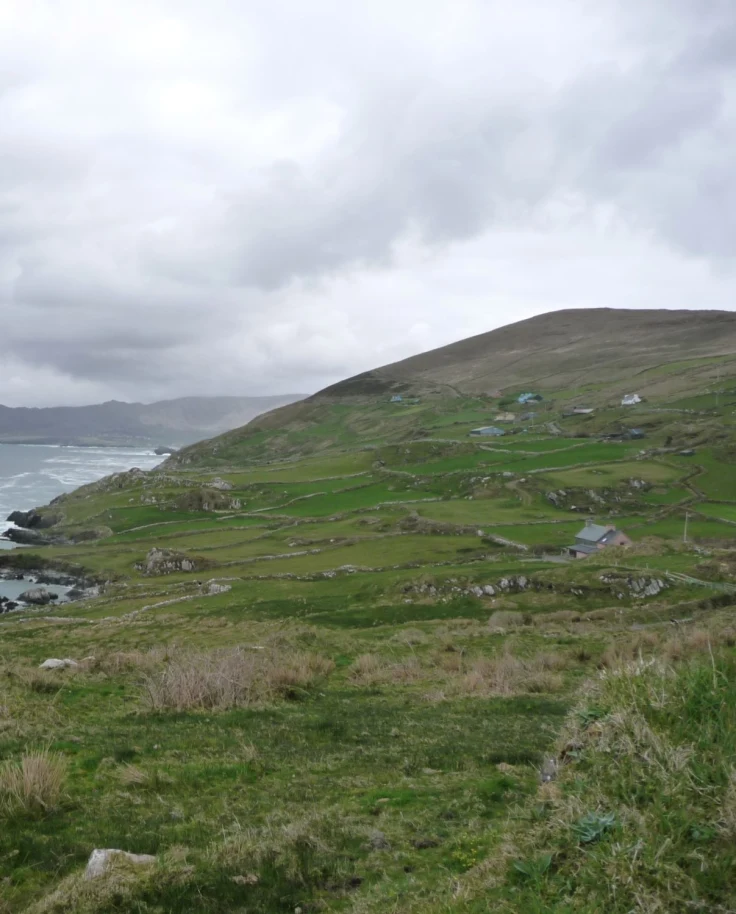 Sea next to grassy hills during a cloudy day in Ireland in May.
