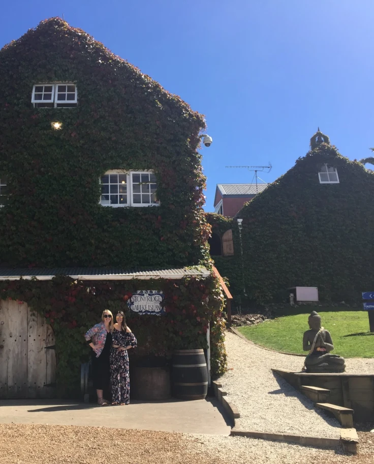 Couple posing in front of a vine-covered barn.