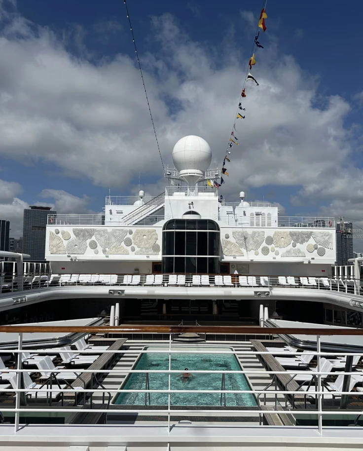 Crusie ship deck with a pool and loungers on a sunny day