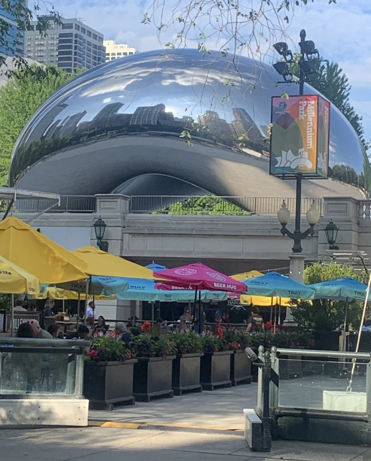 The city is reflected in large abstract silver sculpture.