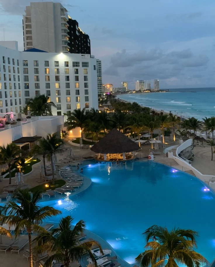 Beachfront skyline with a blue pool and palm trees.
