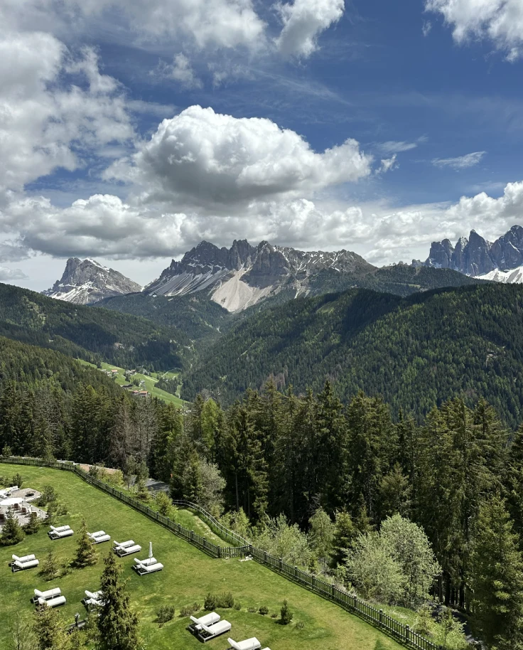 View of the lush valley and mountains on a sunny day dotted with clouds.
