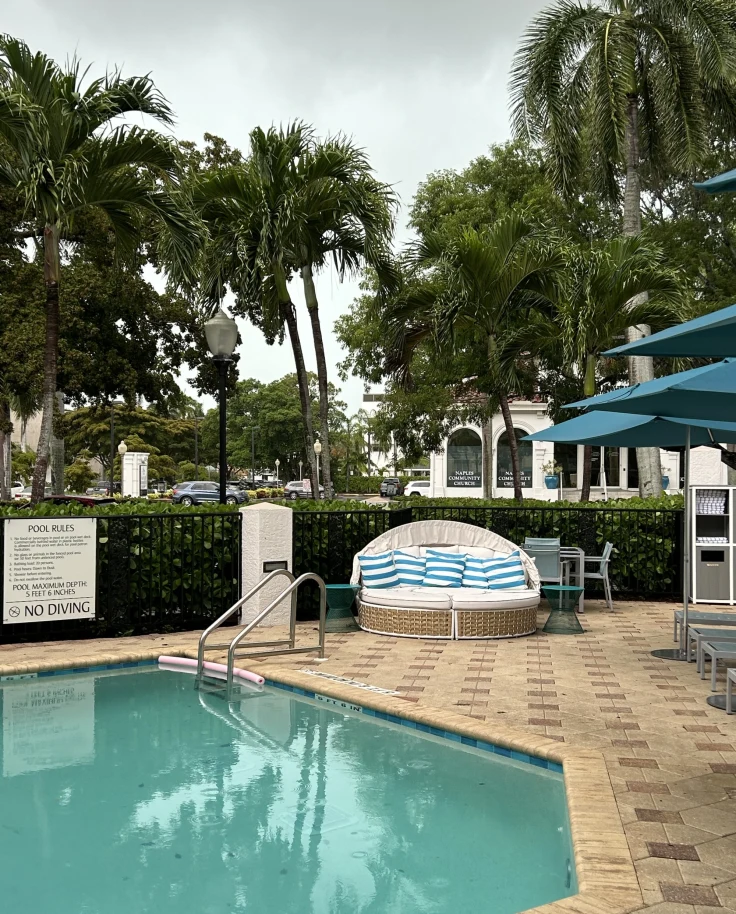 Pool with tiled patio and nearby blue umbrellas.