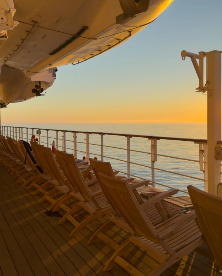 A view from the ship deck overlooking the ocean at sunset.