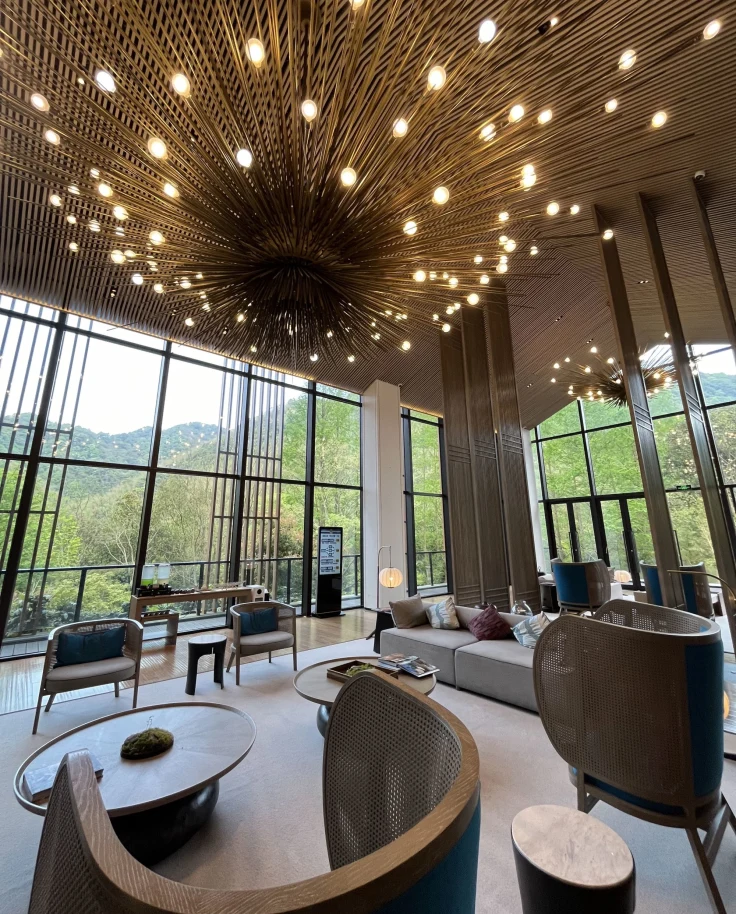 A lobby of a hotel with various seating a large, abstract lighting feature