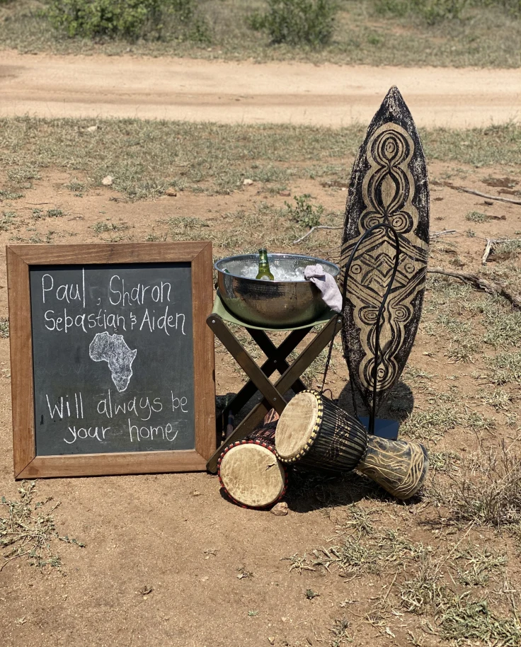 Welcome display with a welcome message on a board, a traditional surf board and drums and drinks in nature