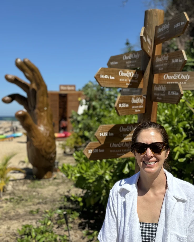 A person posing for a photo in front of a statue of a hand
