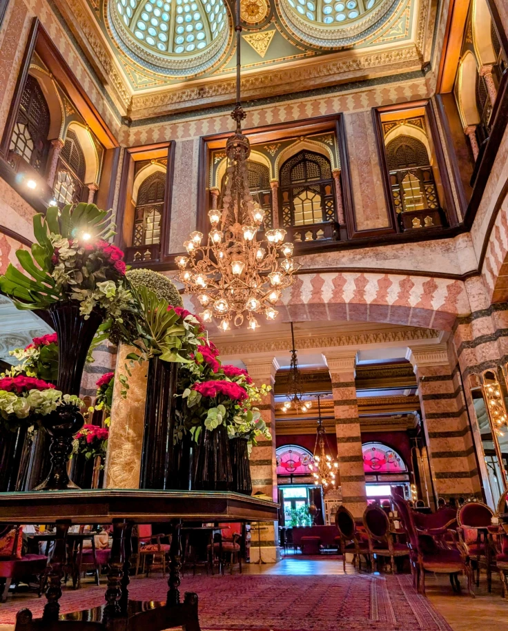 Interior of a luxurious hotel lobby with glass skylights and an Art Deco chandelier.