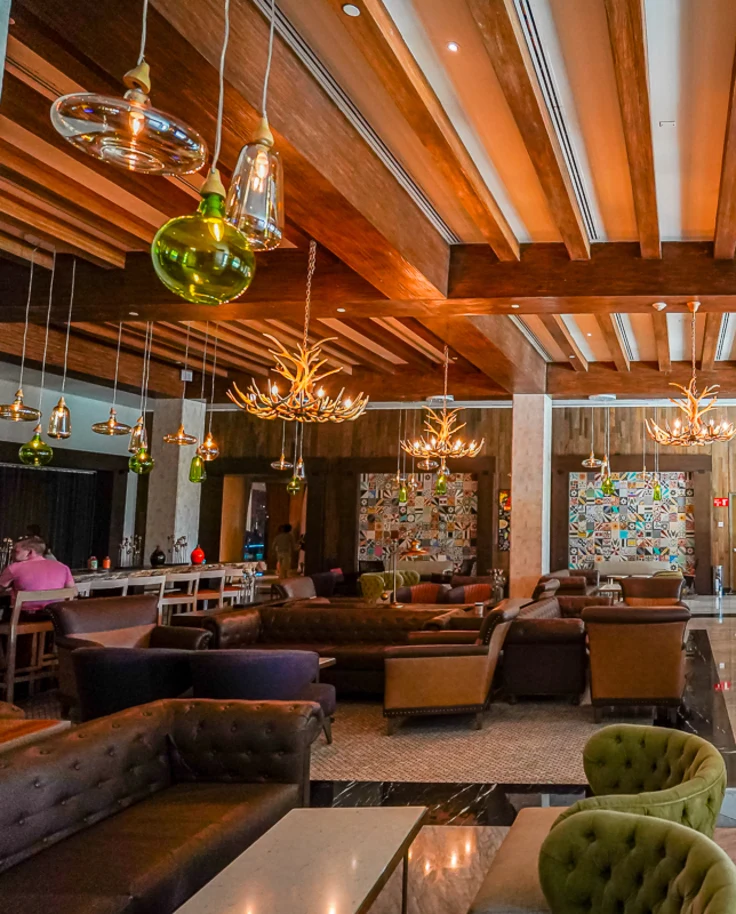 A beautiful hotel interior with paneled ceilings, glass lighting hanging from the ceiling, colorful furniture and a colorfully painted check-in desk.
