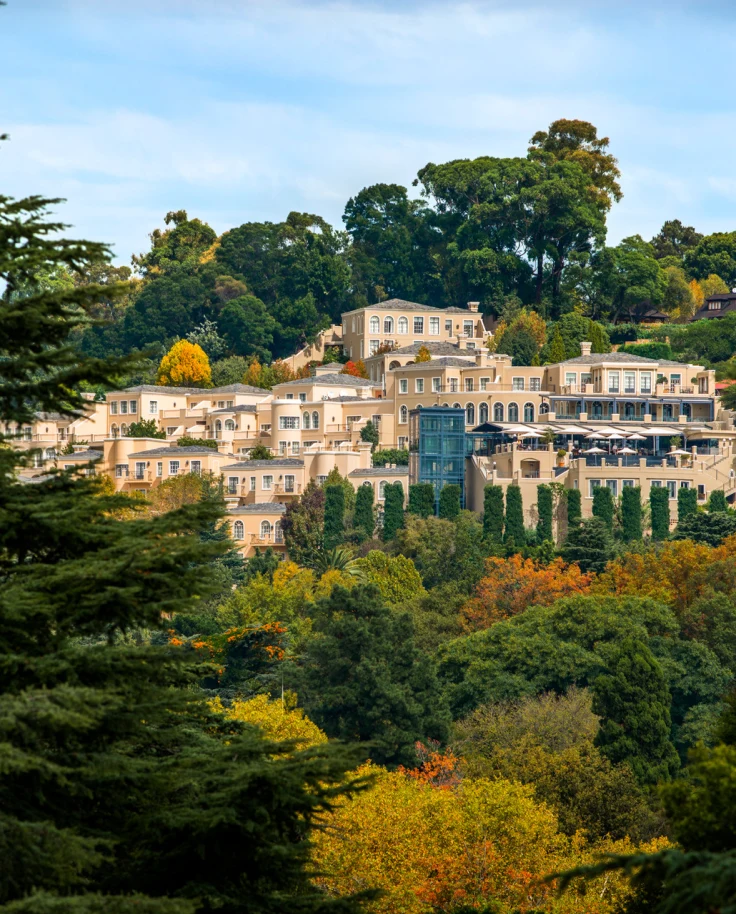 The exterior of the Four Seasons South Africa surrounded by lush forest landscape with yellow, green and orange foliage.