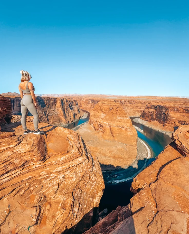 Travel advisor posing at the top of red mountains look out on a valley during the daytime