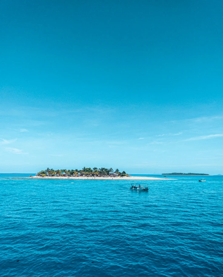 A sea view with a small, tree-covered island in the distance