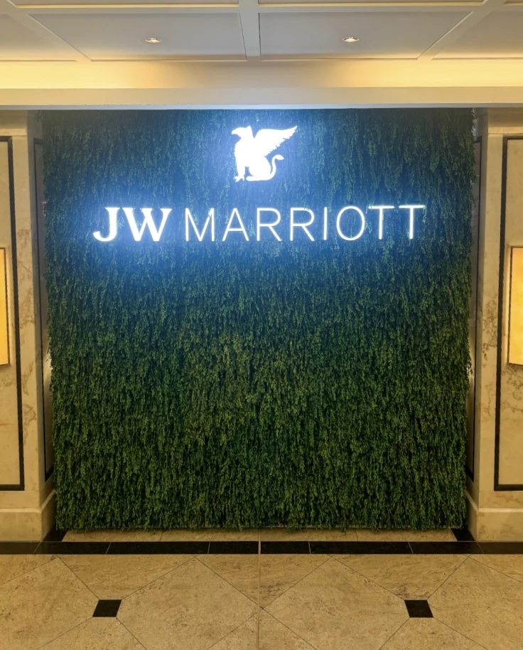 A wall covered in fake grass with a light up sign of the JW Marriott logo