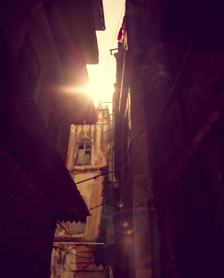 A view of stone buildings with a sliver of sunshine peeking through.