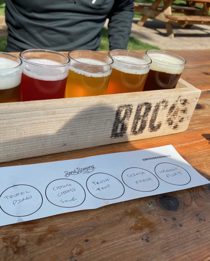 Bend Brewing Company features beer flights on wooden tables in the sunshine.