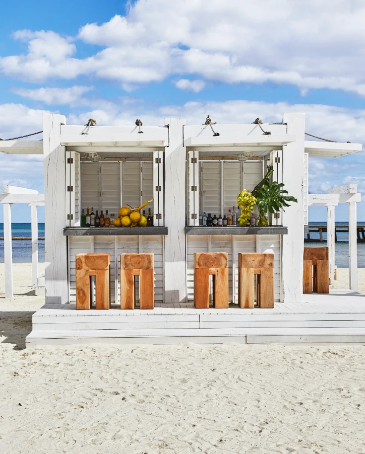 A white beach shack with wooden stools, a bar, citrus and roof coverings in the Riviera Maya, Quintana Roo, Mexico