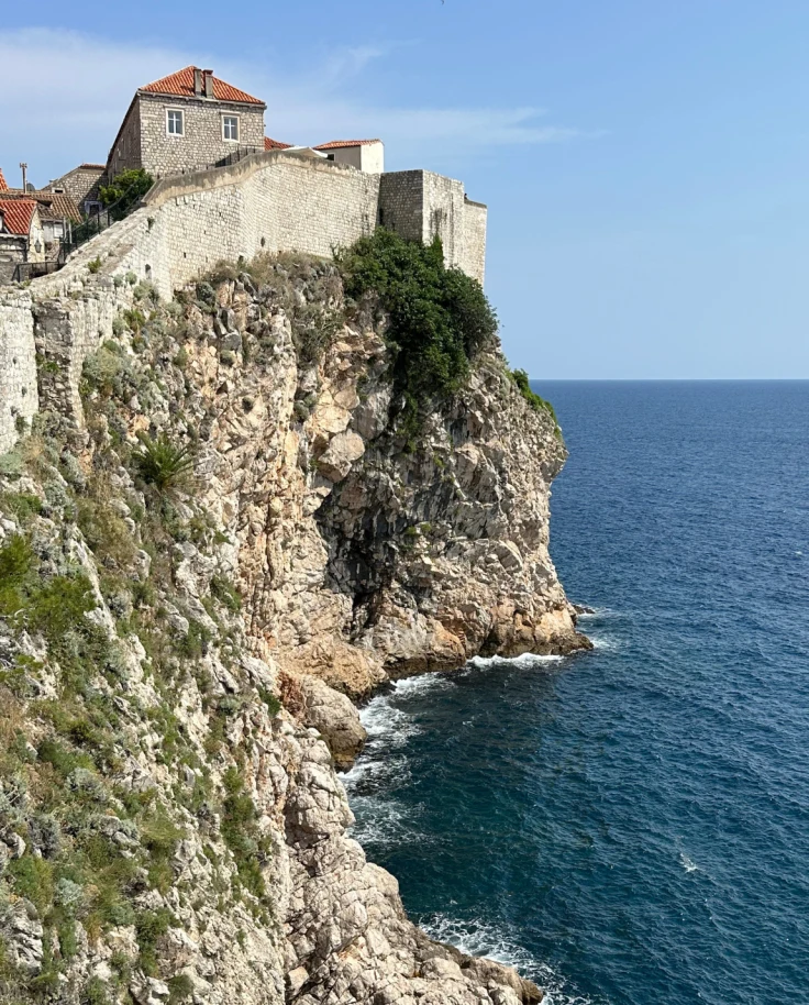 A cliffside next to a body of water with a building on top