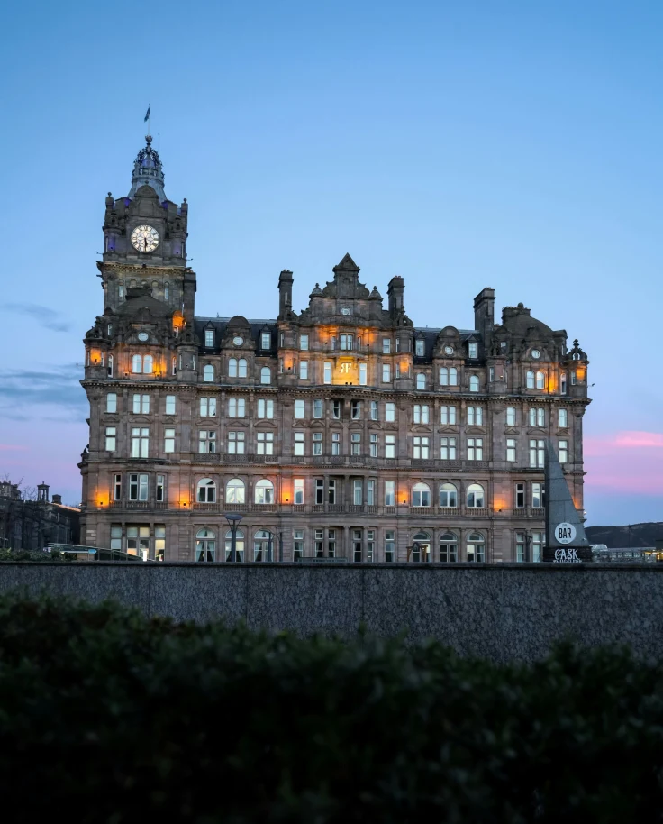 A grand hotel lit up against the fading blue and pinks of the sky at dusk.