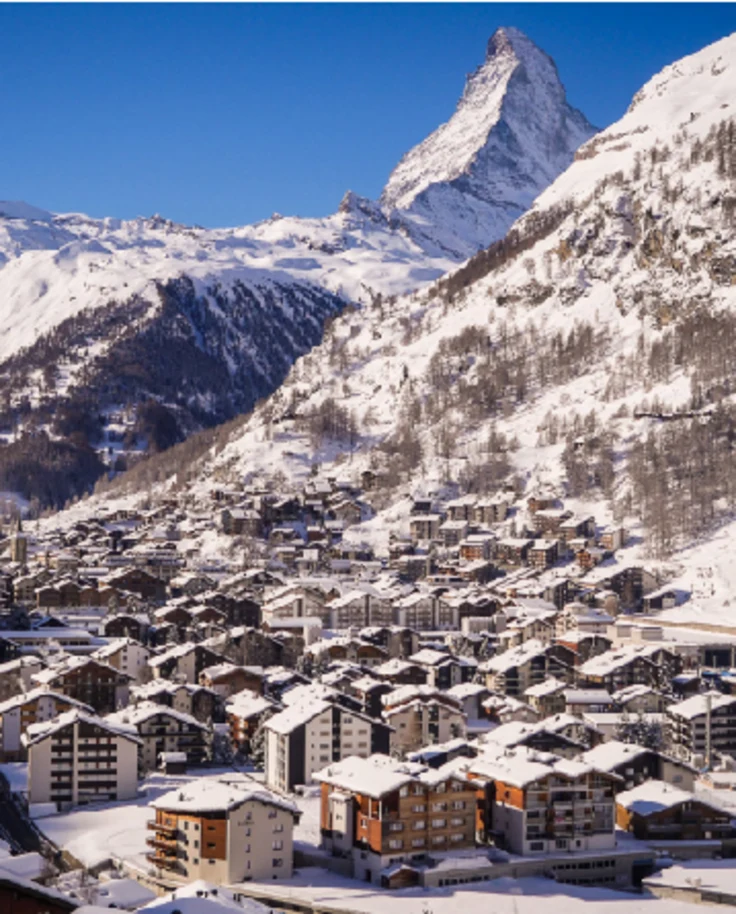 Aerial view of a small town in between snow-covered mountains