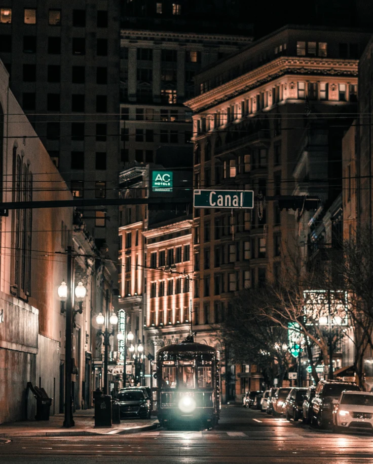 Night view of a street in New Orleans with 4-Star hotels and illuminated buildings, street lamps and a tram.