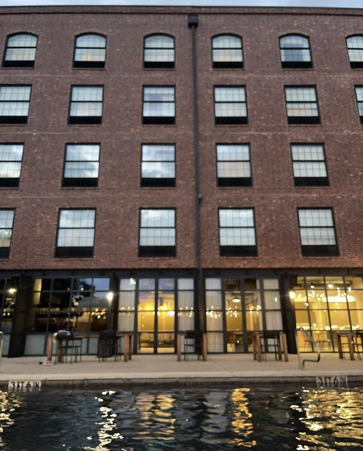 The hotel brick exterior stands tall against a clear sky dotted with clouds at dusk.