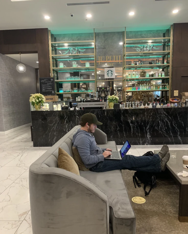 A coffee bar area in a hotel with a person working on a gray couch
