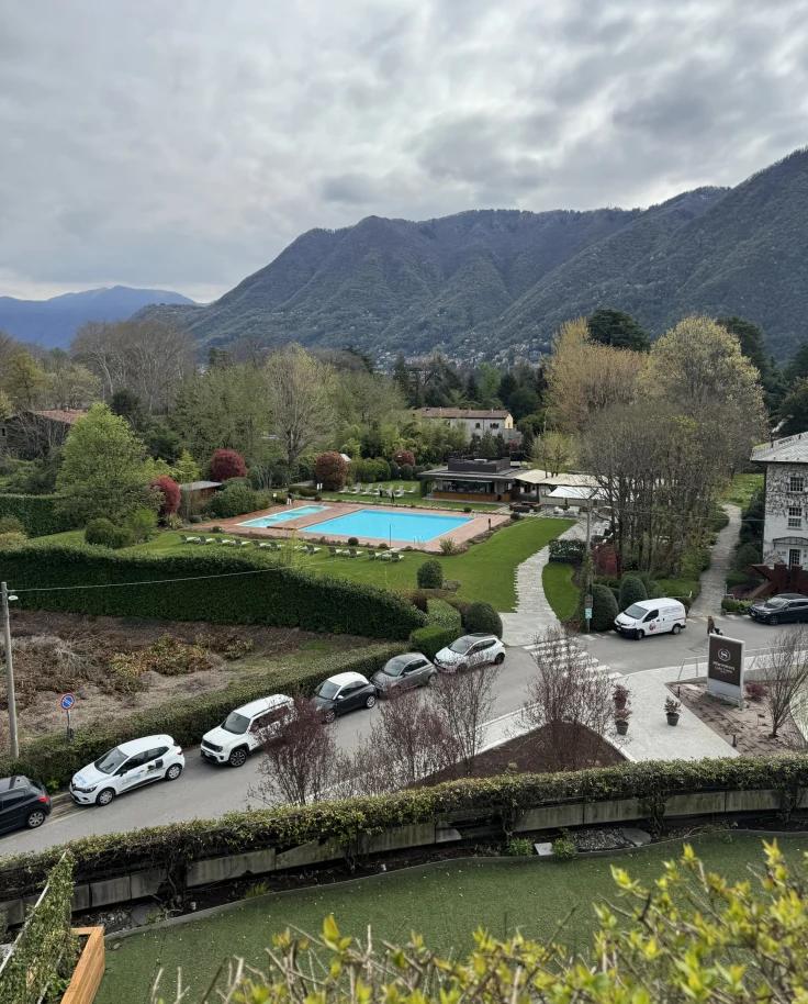 A view of a mountain valley neighborhood with other houses, cars and a backyard pool on an overcast day.