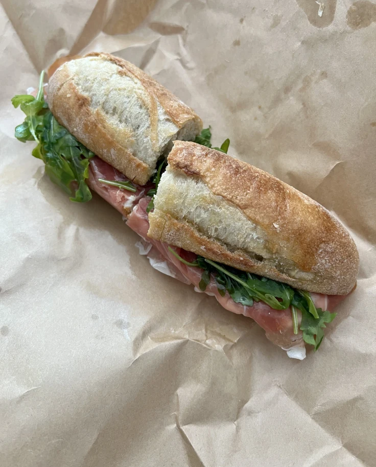 Long bun sandwich with meat and lettuce.