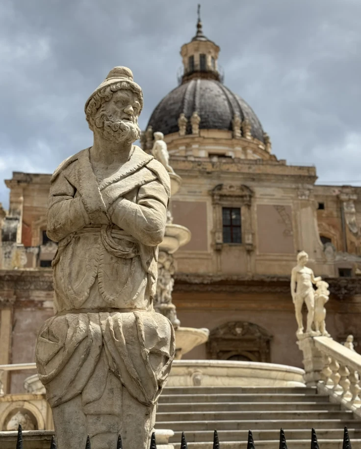A statue of a man in front of an ancient building