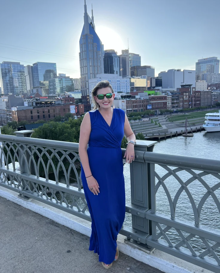 A person standing on a bridge posing for a photograph in front of a city skyline
