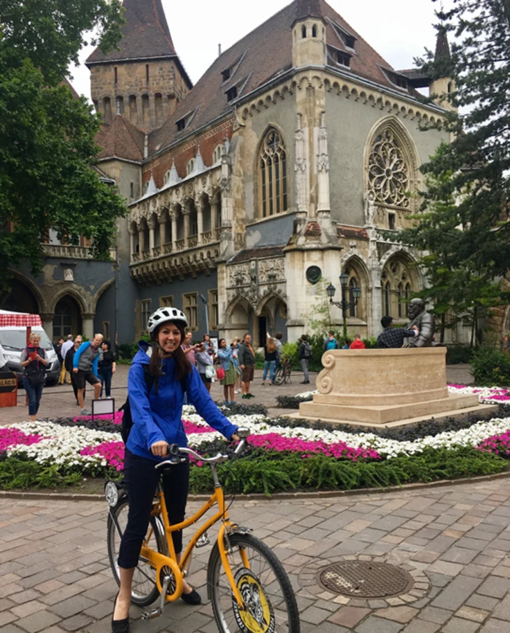 A woman in blue shirt on a bicycle during daytime on a street.