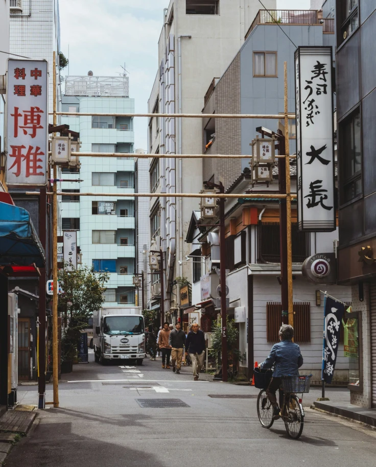 People walking and cycling on a city street in Japan