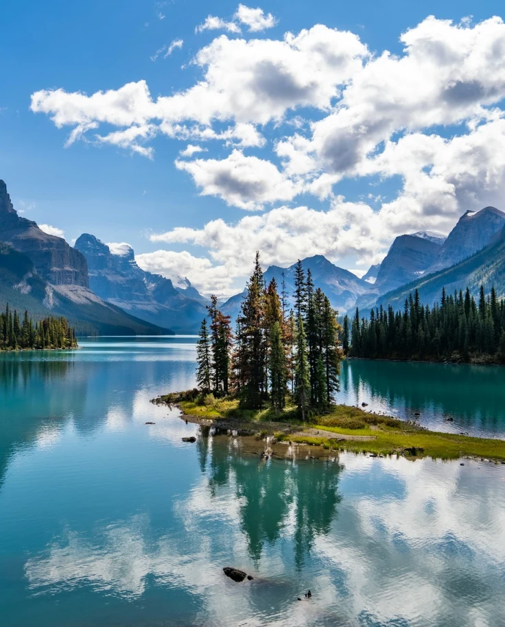 Green trees near beautiful blue lake and mountains in Spirit Island at Maligne Lake in Jasper National Park.