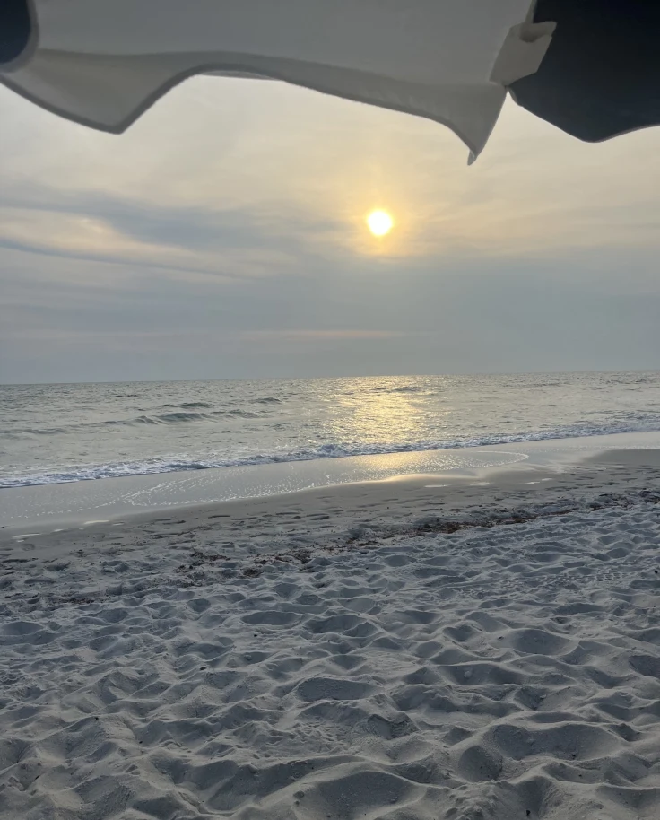 Sunset at the beach under an umbrella.
