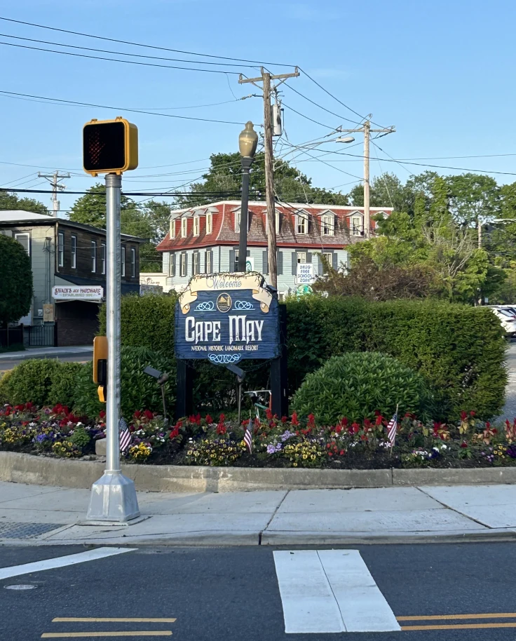 Welcome signage at Cape May on a sunny day surrounded by foliage.