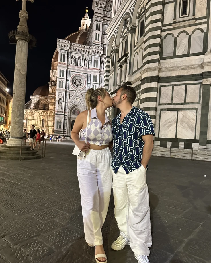 Couple posing in front of historic architecture on a quaint street corner in the evening.